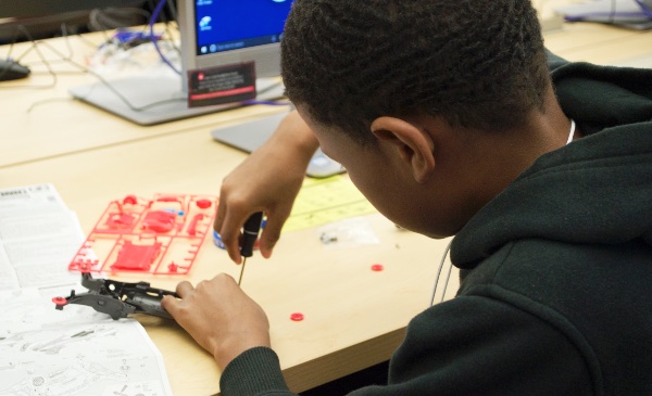 An elementary/middle school student works on a science project with a screwdriver.