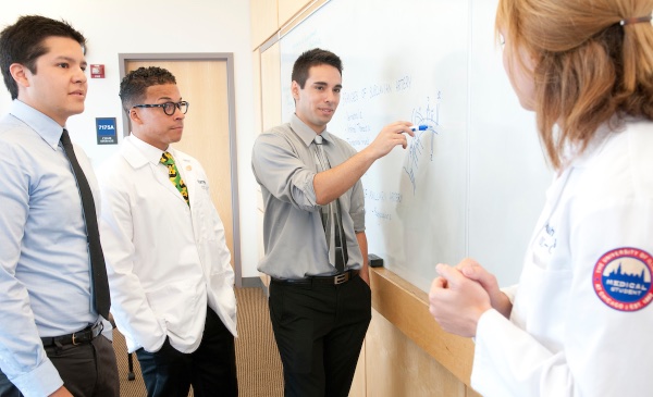 Medical students work on a problem on a white board.
