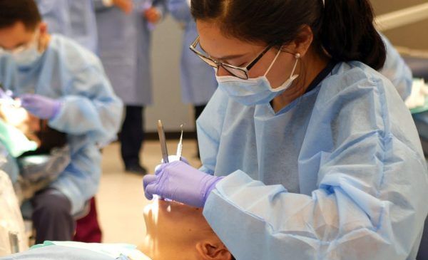 A UIC College of Dentistry student practices an oral exam with a fellow student.