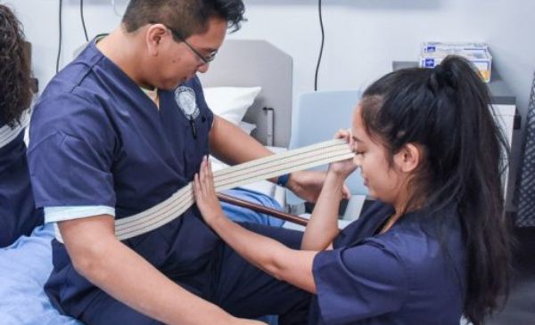 A UIC College of Nursing student practices applying a stability belt to a fellow student.